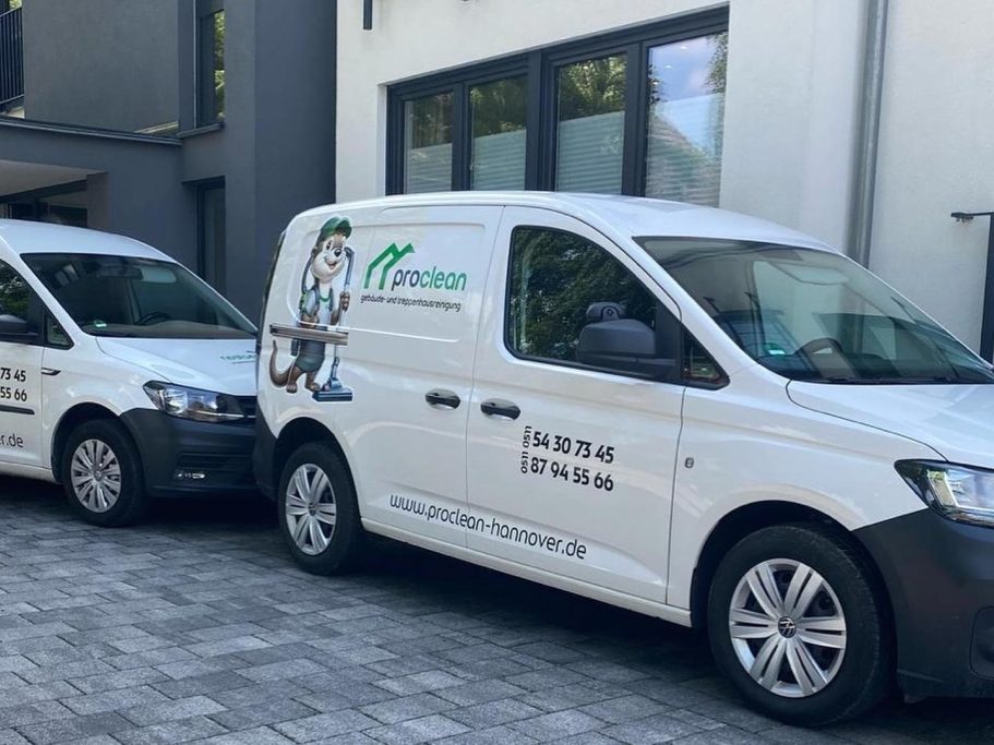 Treppenhausreinigung Hannover Zwei Lieferwagen mit Firmenlogos parken vor einem modernen Gebäude.
