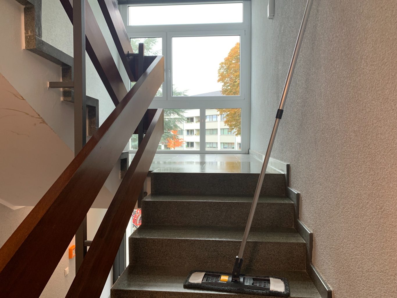 Treppenhaus mit einem Wischmopp und großen Fenstern im Hintergrund.